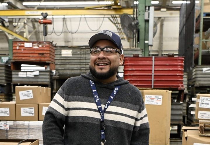An S&C team member smiles in front of supply boxes An S&C team member smiles in front of supply boxes