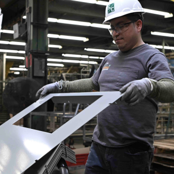 A team member transports a metal component to the next workstation. metal finishing, manufacturing, careers, jobs, production, assembly