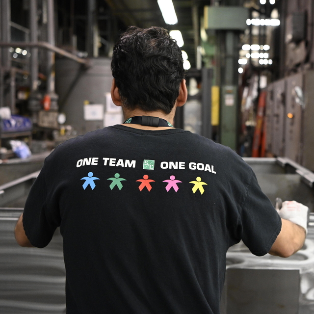 A team member displays S&C's "one team, one goal" slogan