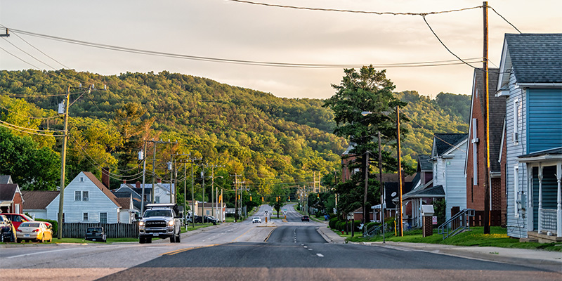 Empty residential road street in small town with sunset and houses