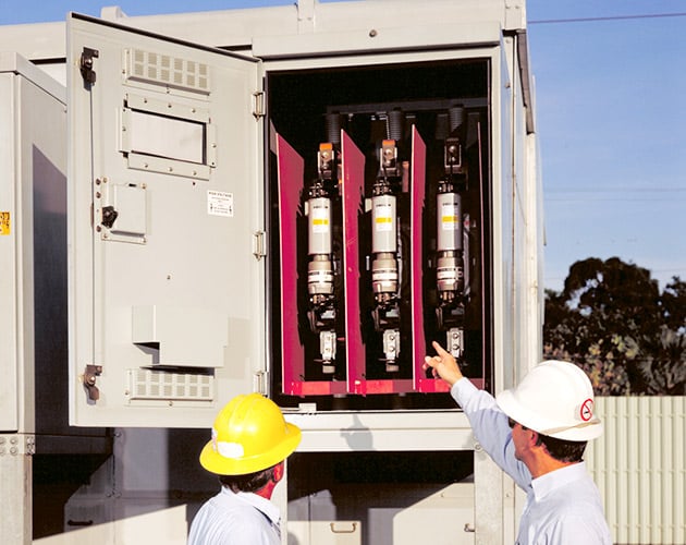 two operators with hard hats on pointing at the high continuous current fuse installed in a metal enclosed unit high-speed fuse, fuse, current fuse